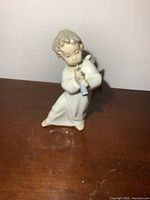 Front view of Lladro angelic figurine playing a flute, showing detailed facial features and flute held with both hands.