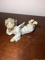 Angel figurine lying on a brown wooden surface shot from front-left angle.