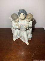 Front view of the Lladro figurine showing three caroling angels holding a music sheet.