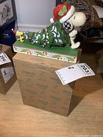Figurine of Snoopy hugging tree atop original Peanuts-themed packaging box