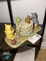 Full view of both Pooh bookends together on shelf showing Pooh facing the back of the well and Eeyore and Tigger on the other side