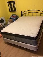 Front view of queen size mattress on box spring with metal frame and headboard