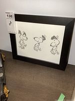 Framed print of three black and white Snoopy sketches with artist signature visible in bottom left corner