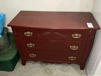 Front view of vintage solid wood painted dresser with three drawers, brass handles, and decorative carving on top drawer.