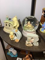 Wide view of Winnie The Pooh collectibles including the perpetual calendar, snow globe, and two resin letters