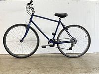 Side profile view of the adult blue mountain bike showing full frame, wheels, pedals, and seat.