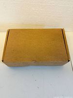 Plain brown cardboard box front view on white surface with no markings.