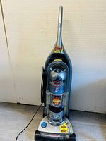 Front view of Bissell Wide Path upright vacuum cleaner showing the handle, dust container, power dial, and labels.