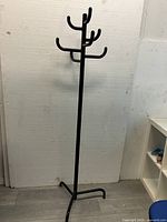 Front view of the black matte finish coat rack stand with multiple hooks and tripod base, displayed against a white background.