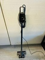 Full view of the vacuum cleaner standing upright with the power cord wrapped around the handle.