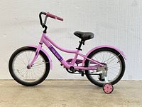 Side view of pink Raleigh kids' bike showing frame, training wheels, tires, and seat.