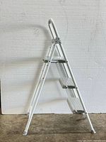 Side profile of the white 3-step ladder showing three metal steps and safety handle at the top.