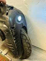 Front-side view showing single tire, round LED headlight, and scuffed housing