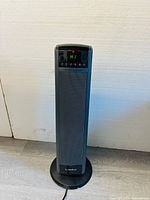Front view of Lasko ceramic tower heater showing the digital display "HI" and control buttons, standing on circular base