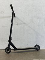 Black scooter with two wheels, T-bar handle and footboard shown against a white background