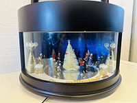 Front view of the snow globe showpiece with visible holiday scene and Christmas tree inside a glass dome.