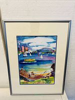 Framed watercolor art showing Sydney Harbour with Opera House, Harbour Bridge, boats, people fishing on shore. Silver frame with double matting.