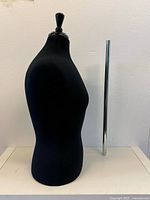 Side view of the black female mannequin torso with separate chrome metal pole standing next to it.