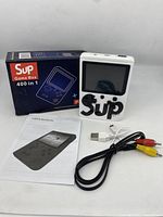 Sup Game Box 400-in-1 gaming handheld with packaging, user manual, USB charging cable, and RCA AV cable all shown.