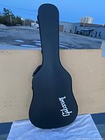 Front exterior view of black hard shell Gibson guitar case with white Gibson logo.
