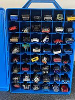 Interior view of the blue plastic carrying case with 48 Hot Wheels cars neatly stored in separate compartments.