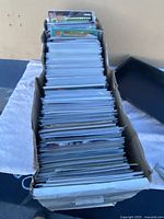 Full view of the cardboard box filled with comic books arranged upright, all in protective sleeves.