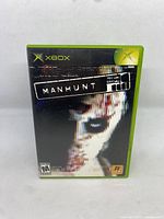Front cover of Manhunt game for Original Xbox showing title and artwork.