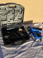 Blue Mastercraft heat tool alongside black plastic carrying case with insert slots for attachments