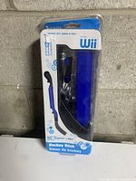 Nintendo Wii Hockey Stick accessory in original sealed package showing black and blue plastic stick attachment and wrist strap inside packaging.