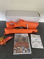 Top view of game box showing orange gun controller, game case, and compass/whistle accessory.