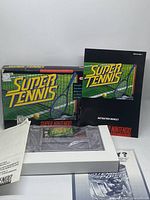 Super Tennis game cartridge, original box and instruction manual with handheld game visible inside plastic.