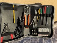 Open tool kit showing all tools organized inside including soldering iron, screwdrivers, wire cutters, desoldering pump, solder wire spools and zip ties.