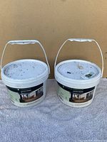 Two white buckets with handles containing Leadvision Elegance Premium deck clips and screws