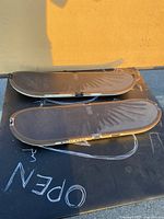 Two brown snowboard-style Tony Hawk video game controllers placed on a black surface