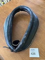 Top-down view of an antique leather horse collar showing the worn surface and decorative studs edge.