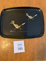 Top view of the rectangular black tray featuring two gold roadrunner bird motifs and a signature.