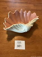 Photo of the ceramic shell bowl showing pink interior and white exterior on wood surface with lot tag