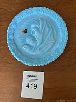Blue round glass plate with raised relief of Madonna and sleeping child, floral border, and inscription 'Mother's Day 1971'.