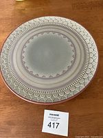 Top view of the round Schramberg ceramic pedestal cake plate showing the detailed embossed pattern with rose accents and smooth central surface.