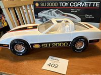 Side view of the white Shell Corvette SU 2000 toy car showing Shell and SU 2000 decals and Shell branded tires with chrome hubs alongside its original box.
