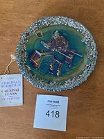 Close-up view of the vintage Fenton carnival glass plate showing embossed man working scene and floral border with iridescent finish.