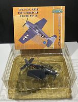 Diecast airplane coin bank model inside clear plastic packaging, showing airplane detail and stand.