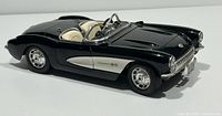 Black 1957 Chevrolet Corvette convertible die-cast model by Burago, angled side view showing sleek body design and detailed wheels.