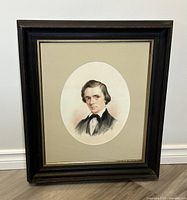 Full view of the framed and matted portrait print showing the black wooden frame and beige mat.
