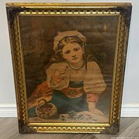 Full view of the antique framed print 'Strawberry Girl' showing the subject and ornate frame with visible wear.