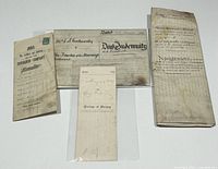 Four antique legal documents laid flat showing front and partial backsides including vellum indenture and insurance policy paper.