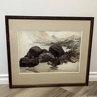 Full view of the framed watercolour painting showing rocky shore and distant hills.