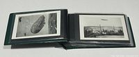Open green binder showing black and white Zeppelin postcards in sleeves