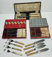 Photo showing boxed and unboxed vintage flatware sets including Coronet butter spreaders, Sheffield butterknives, and fish server set