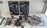 Photo showing two Mastercraft 12-piece combination wrench sets in original packaging plus assorted loose tools including wrenches, sockets, pliers, clamps.